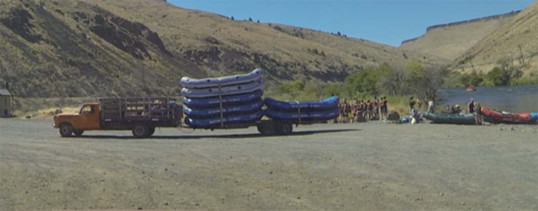 Truck backing a trailer full of rafts to the water
